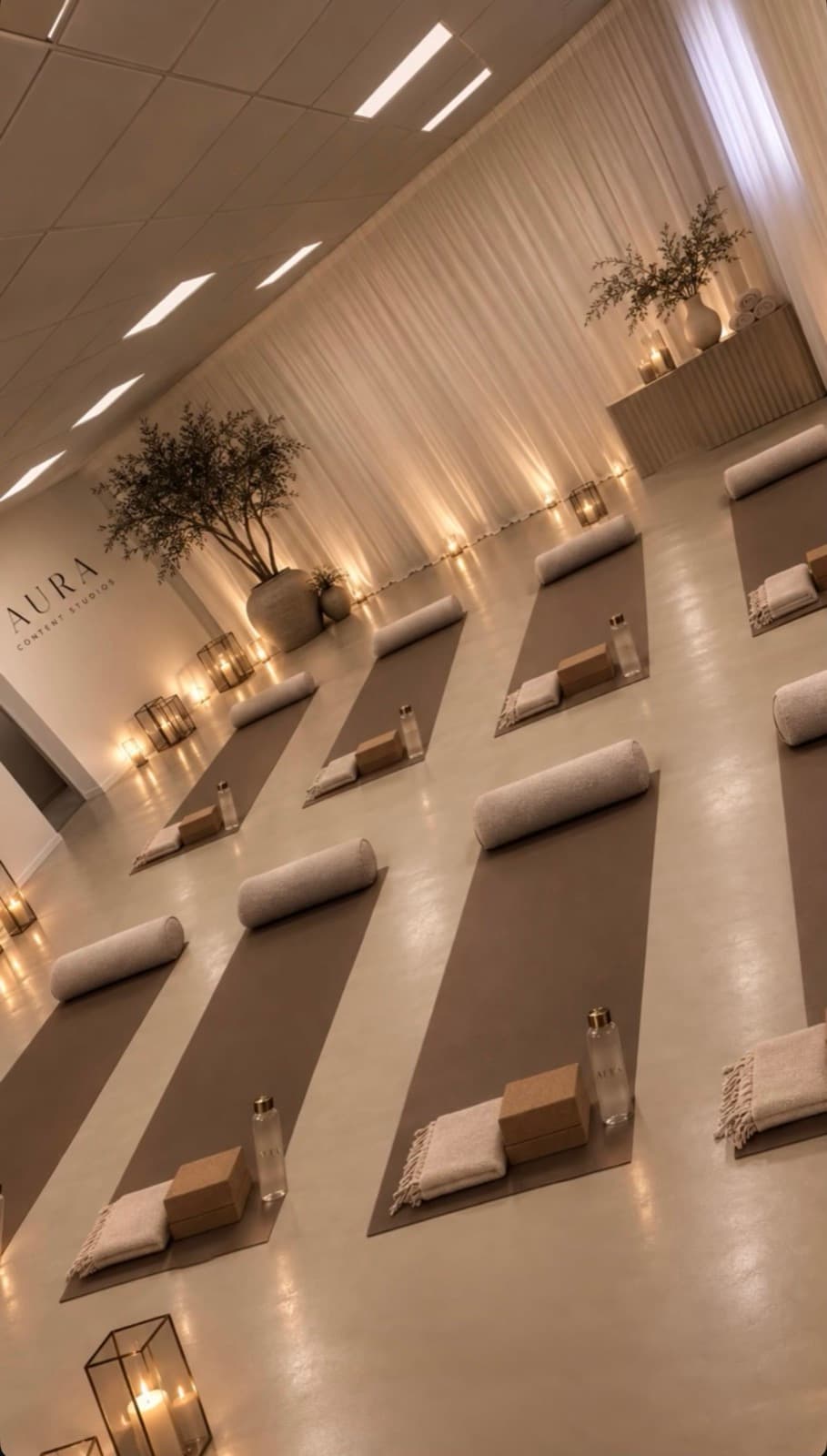 Rows of yoga mats and candles styled for a wellness event, with the studio's wall signage visible